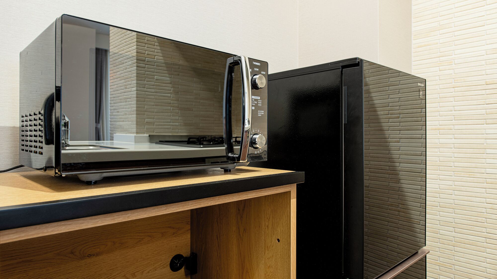 Una cocina con microondas integrado y un refrigerador negro.