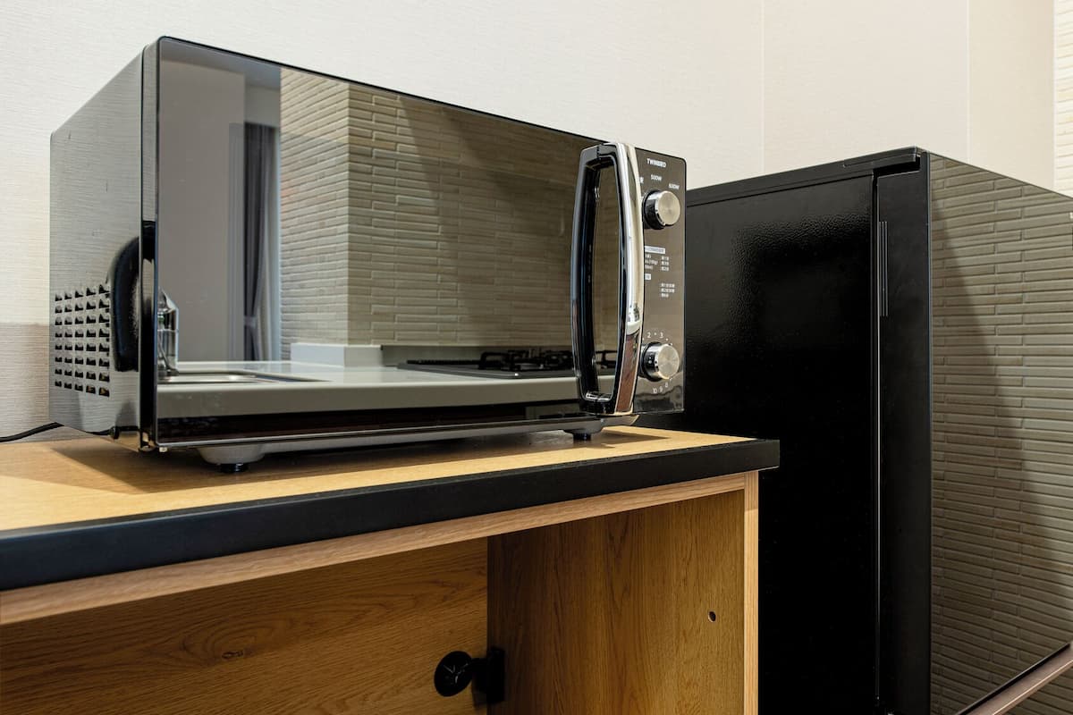 Une cuisine équipée d’un four à micro-ondes encastré et d’un réfrigérateur noir.