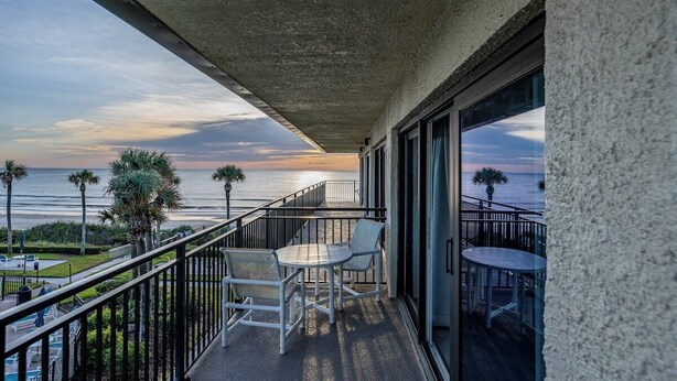 Een balkon met uitzicht op de oceaan, een tafel en stoelen.