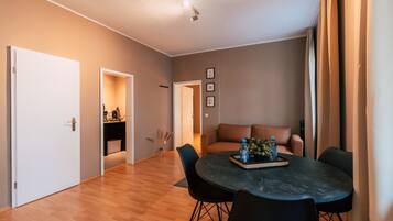 A modern living room with a round table, black chairs, a brown sofa, and a dining area.