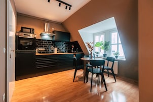 Una cocina moderna con encimera negra, horno empotrado y comedor con mesa y sillas redondas.