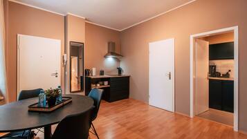 Een moderne keuken met een fornuis, spoelbak en kasten. Er is een eethoek met een tafel en stoelen.