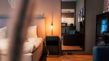 Un dormitorio moderno con cama, mesita de noche, lámpara y vista al área de estar.