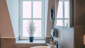 A bathroom with a window, a potted plant, and a mirror. - Luga Homes - Chausseehaus (Leipzig)