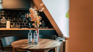 Een ronde houten tafel met twee waterflessen en een bloevas.