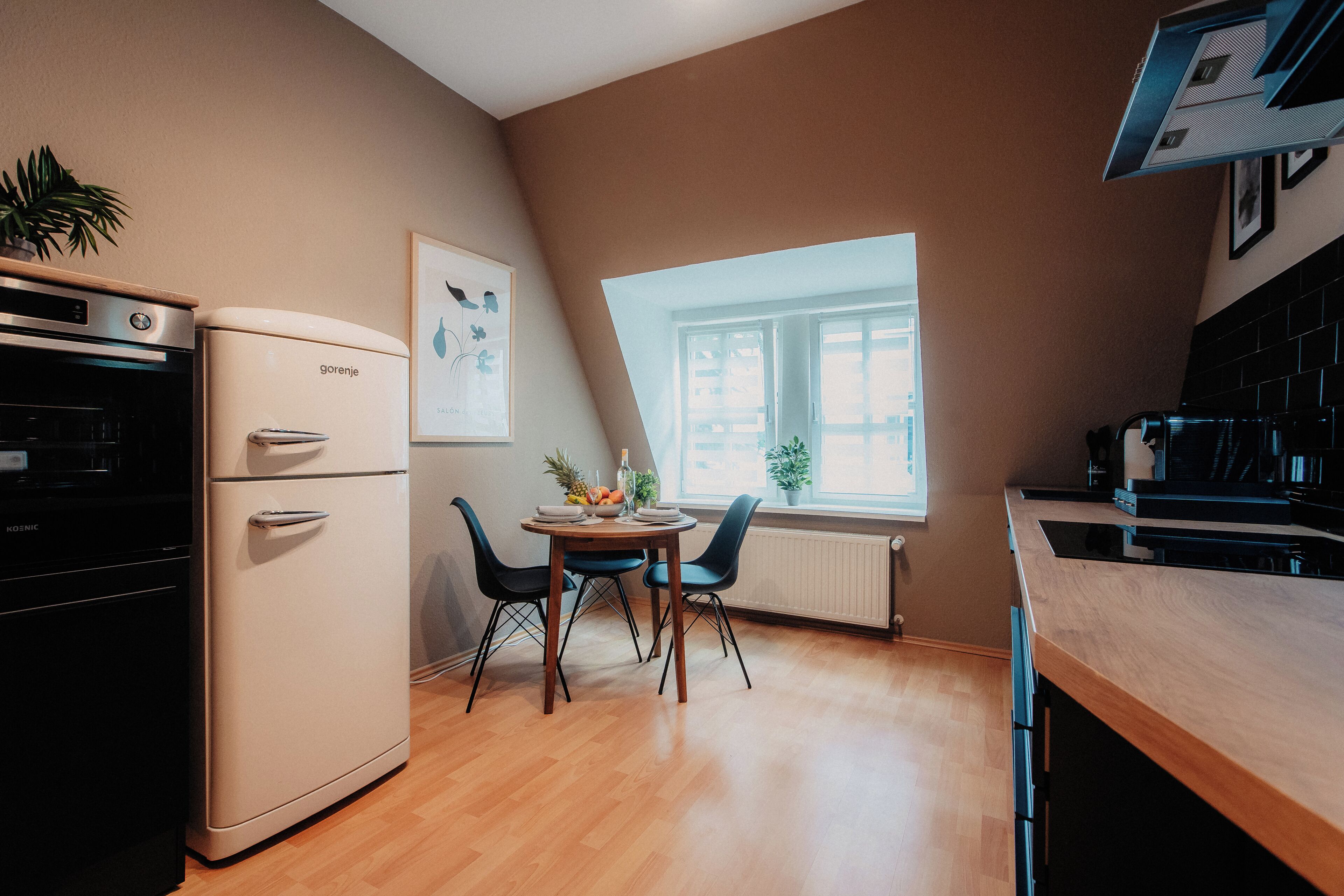 A compact kitchen with a refrigerator, oven, and a dining area with a table and chairs.