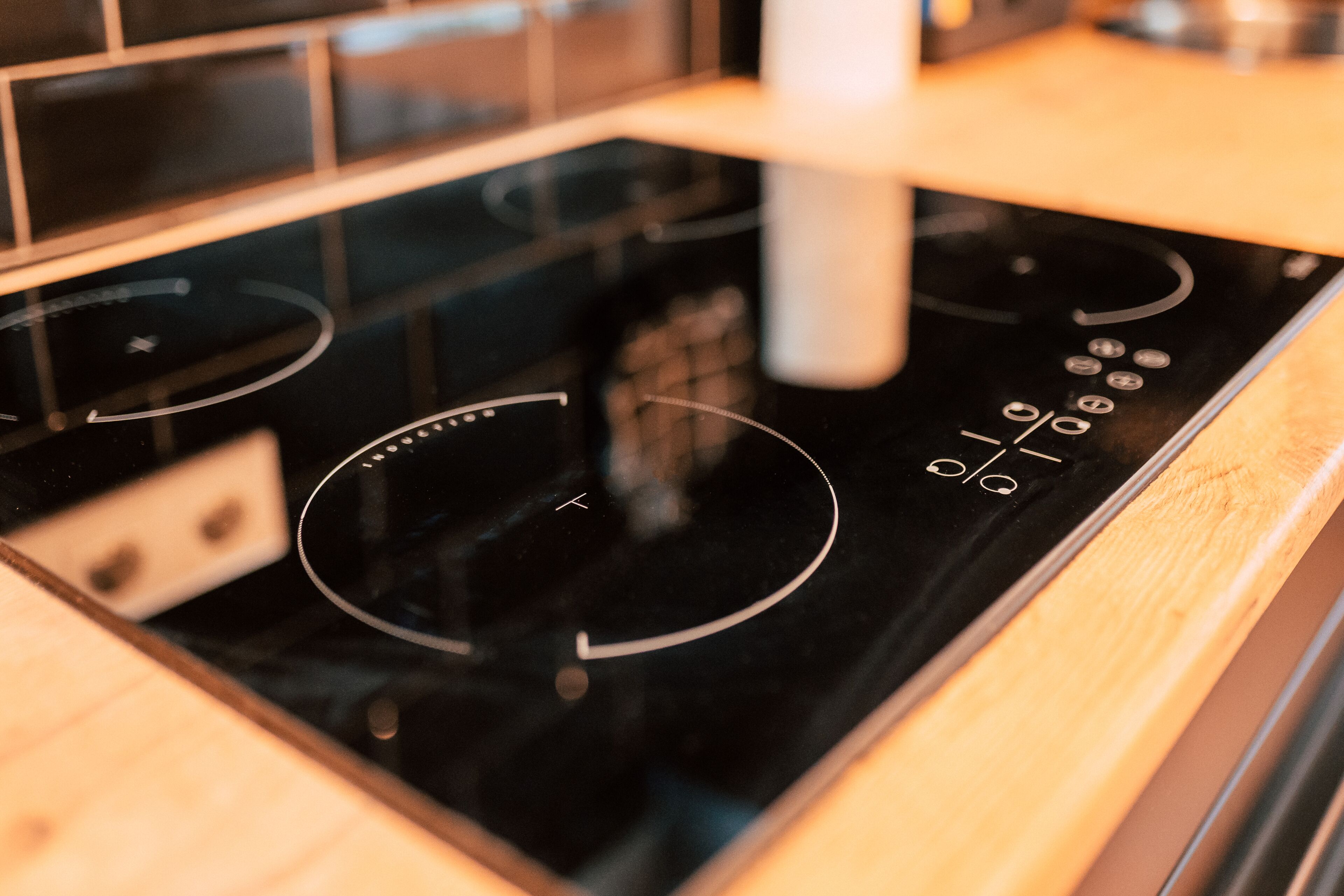 A kitchen with a black induction cooktop and wooden countertops.