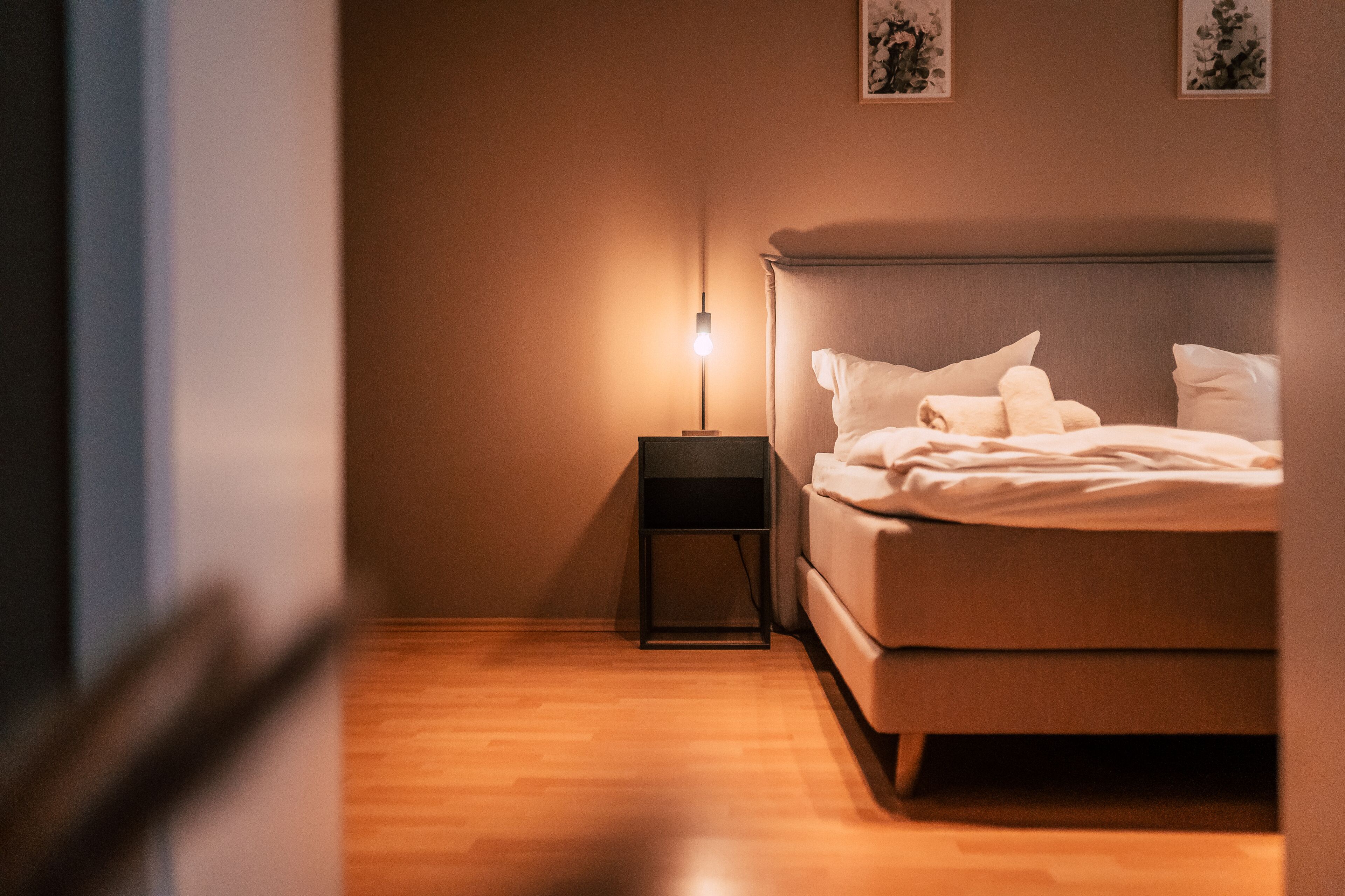 Uma cama bem arrumada com almofadas e mesa de cabeceira com abajur.