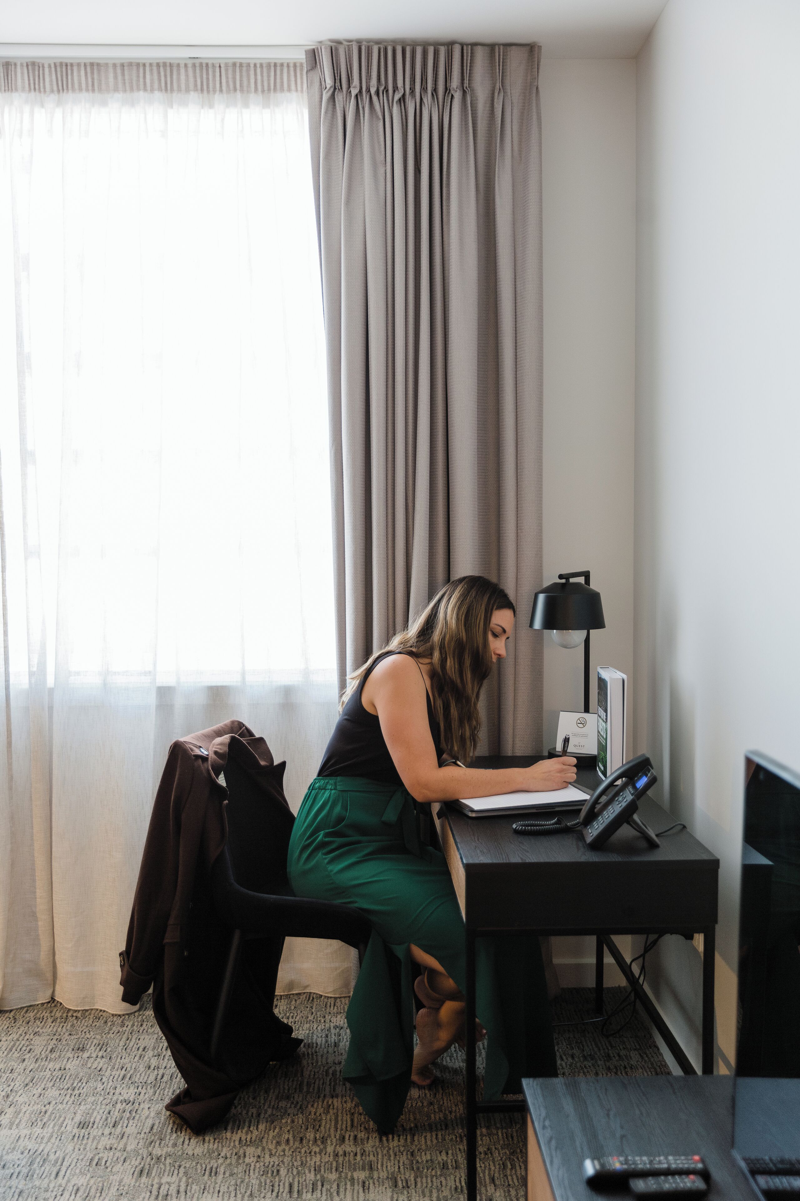 Una habitación con escritorio, laptop, lámpara y televisor.