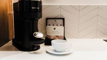 A coffee maker, a cup, and a welcome card on a kitchen counter.