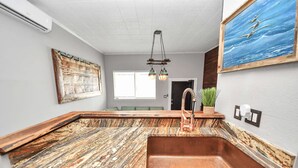 Una cocina con una isla grande, un fregadero, luces colgantes y un cuadro en la pared.