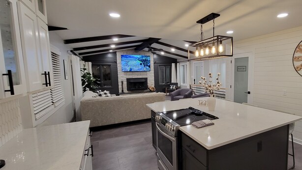 A modern kitchen with a central island, a built-in oven, and a large clock on the wall. - Stunning and Completely Remodeled Ranch Home! Walk to Downtown & Marina! (Port Washington)