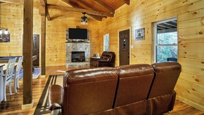 A log cabin interior with a fireplace, leather sofa, dining area, and a television. - This Amazing home has lots to offer! wonderful hot-tub , pool table & seclusion (Townsend)
