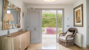 A modern hallway with a wooden console, a mirror, and a wicker chair. - Gorgeous home in Marbella (Marbella)