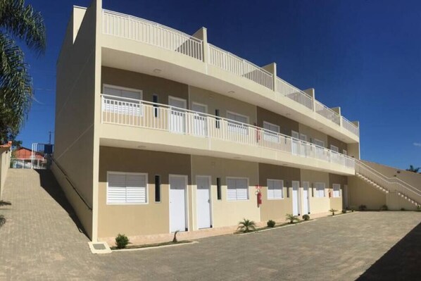 A multi-story hotel with balconies, a covered parking area, and a clear sky.