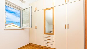 A room with a large wardrobe, a window with a view of a house, and wooden flooring. - 1 bedroom awesome apartment in Makarska (Makarska)