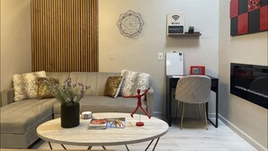 A modern living room with a sofa, a round coffee table, and a red chair. There is a wall-mounted shelf with a WiFi sign and a small plant. - Redman Rental Guesthouse (Tucson)