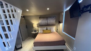 A bedroom with a bed, bedside tables, a lamp, and a TV mounted on the wall. - Redman Rental Guesthouse (Tucson)