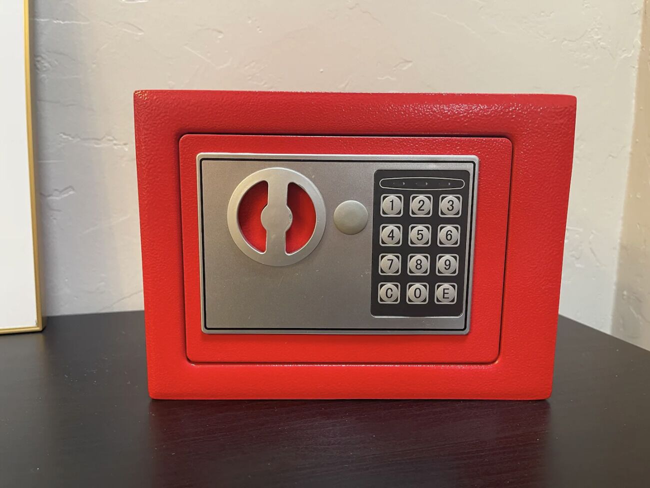 A red safe with a keypad lock and a keyhole.