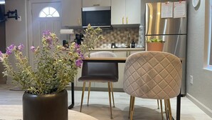 A modern kitchen with a dining area, featuring a potted plant, a quilted chair, and stainless steel appliances. - Redman Rental Guesthouse (Tucson)