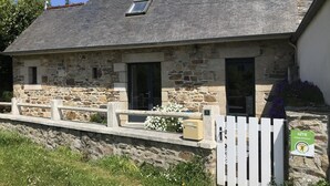 A stone house with a sloped roof, a small window, and a white fence. - Ty Rozenn Gwenn - PLOUGUIEL (PLOUGUIEL)