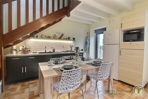 A modern kitchen with dark cabinets, a wooden dining table, and white chairs.