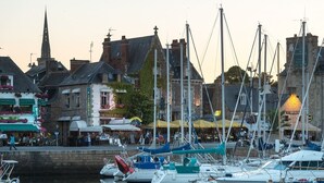 A marina with boats docked, a church spire in the background, and a hotel named "L'ESCALADE". - Ty Rozenn Gwenn - PLOUGUIEL (PLOUGUIEL)