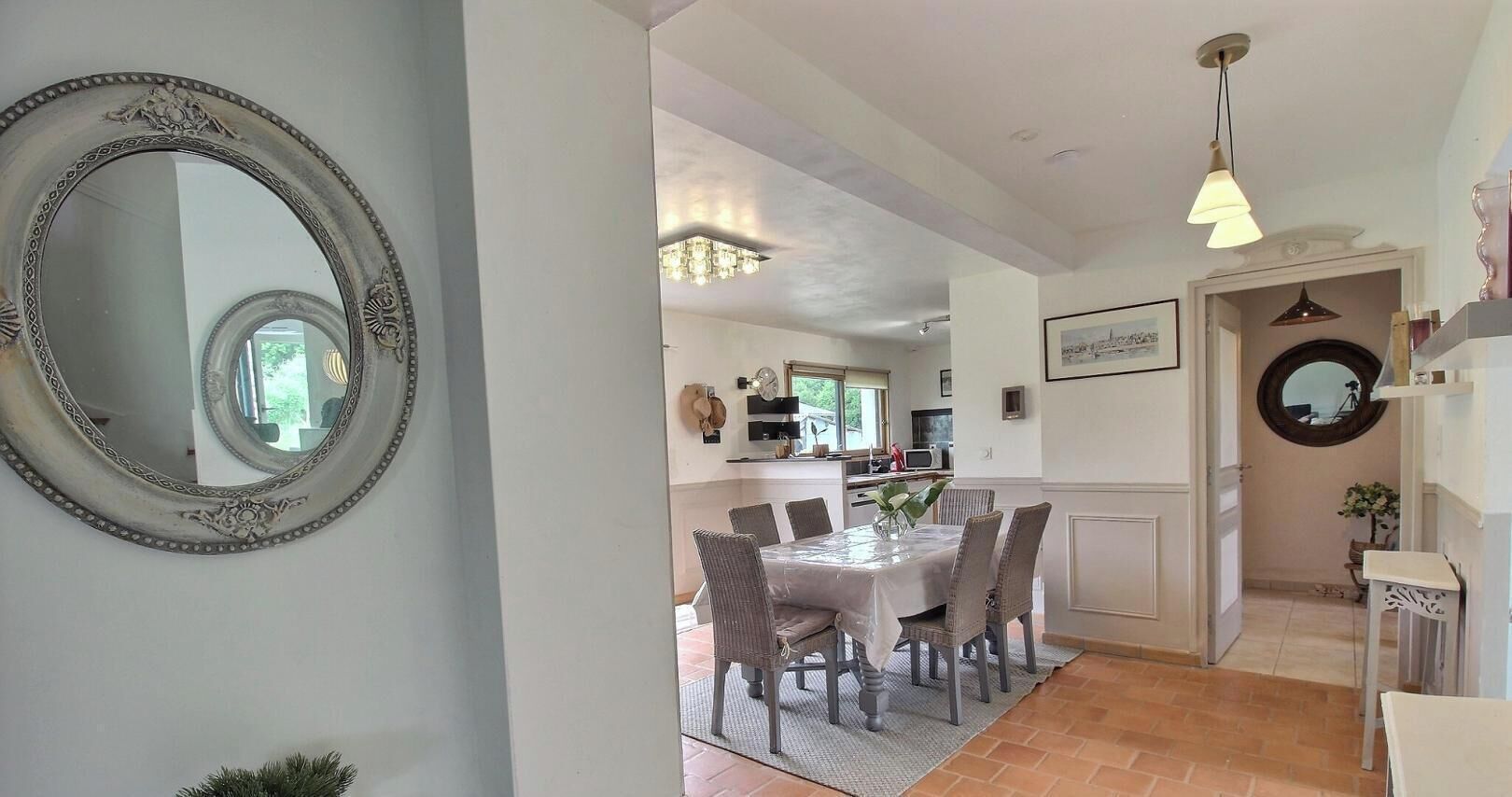 A dining area with a table and chairs, a chandelier, and a mirror on the wall.