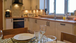 Een keuken met witte kastjes, een magnetron, een fornuis en een raam met uitzicht.