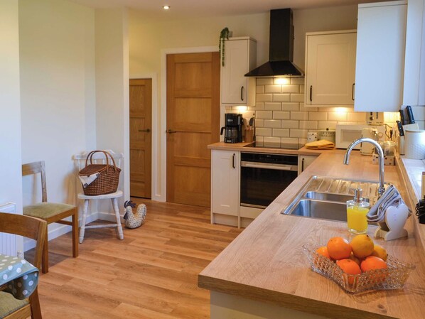 A kitchen with a wooden countertop, a sink, and a fruit bowl. - Low Chibburn Farm Cottage (Widdrington, near Druridge Bay)