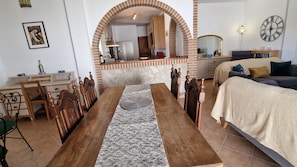 Een ruime woonkamer met een eethoek, keuken en een gezellige slaapkamer.