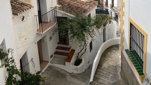 Eine enge Straße mit traditionellen Gebäuden, einer sichtbaren Treppe und einem klaren Himmel.