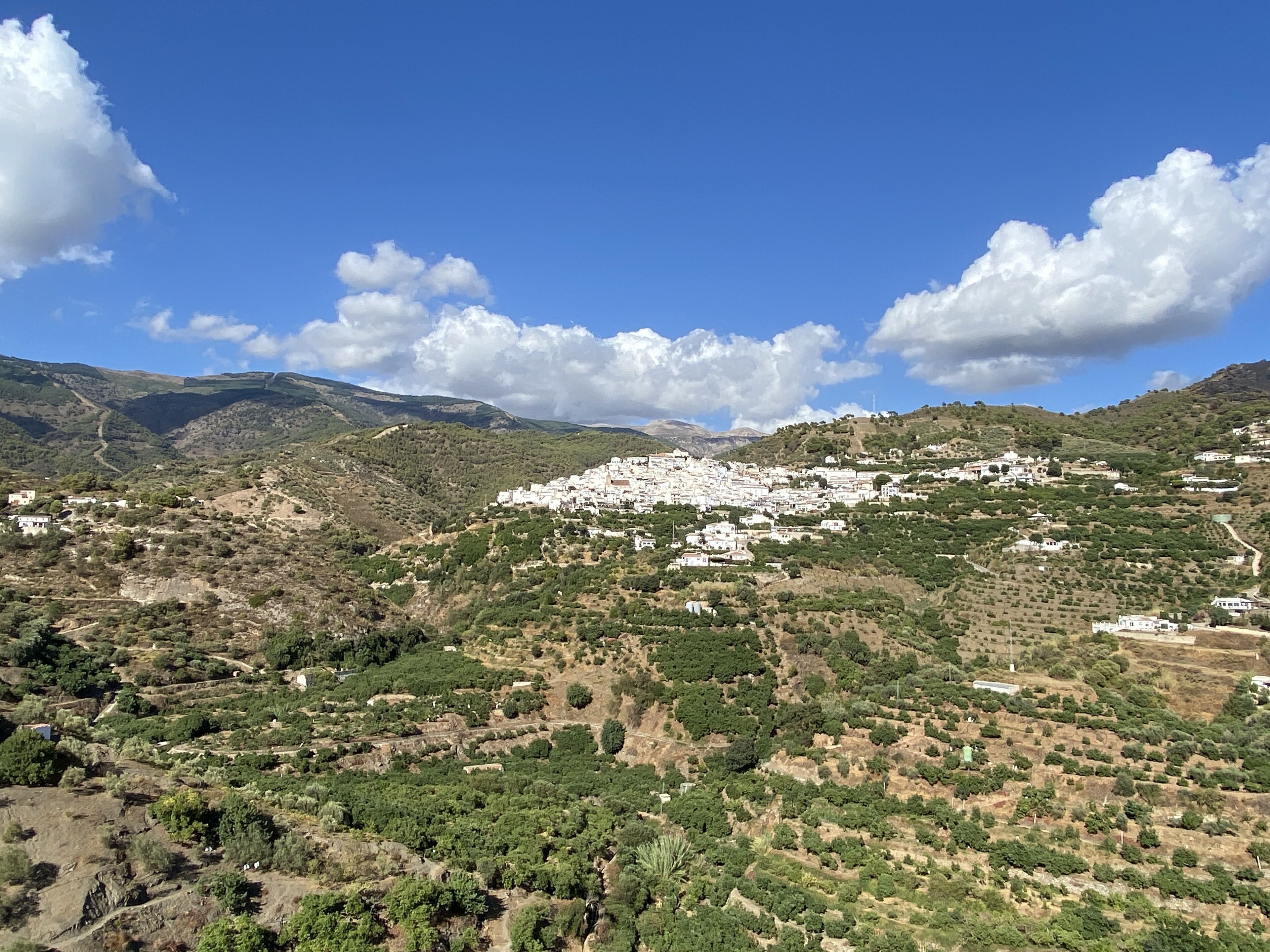 Un paysage montagneux avec un village blanc niché au milieu de collines verdoyantes.