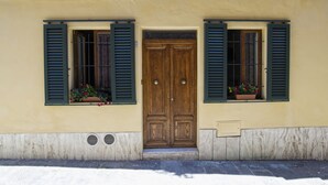 Un bâtiment doté d’une porte à double battant en bois, de deux fenêtres avec volets et de jardinières posées sur les rebords de fenêtre.