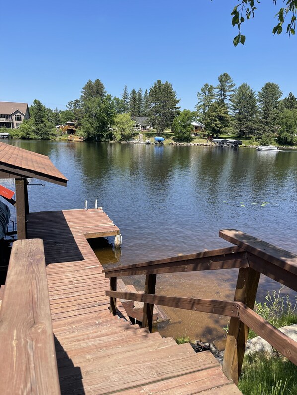 A wooden dock extending into a calm lake, surrounded by trees and houses.