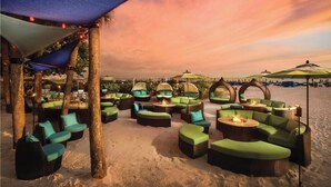 Una zona relax sulla spiaggia con posti a sedere all'aperto e ombrelloni, con vista sul mare.