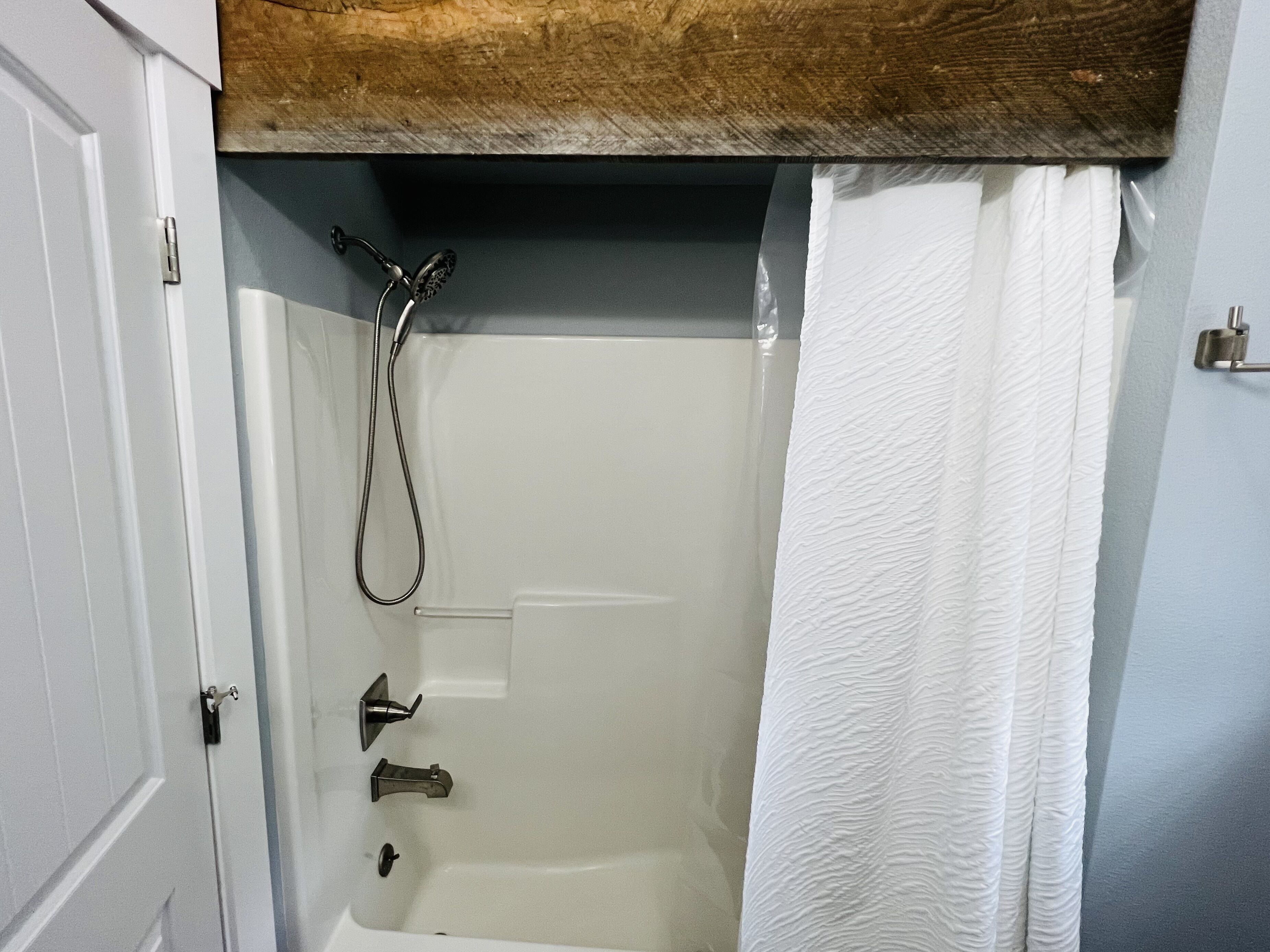 A bathroom with a bathtub, shower, and a wooden ceiling.