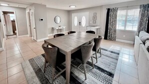 A modern living room with a dining table, sofas, and a kitchen area.