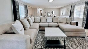 A modern living room with a sectional sofa, a coffee table, and patterned curtains.