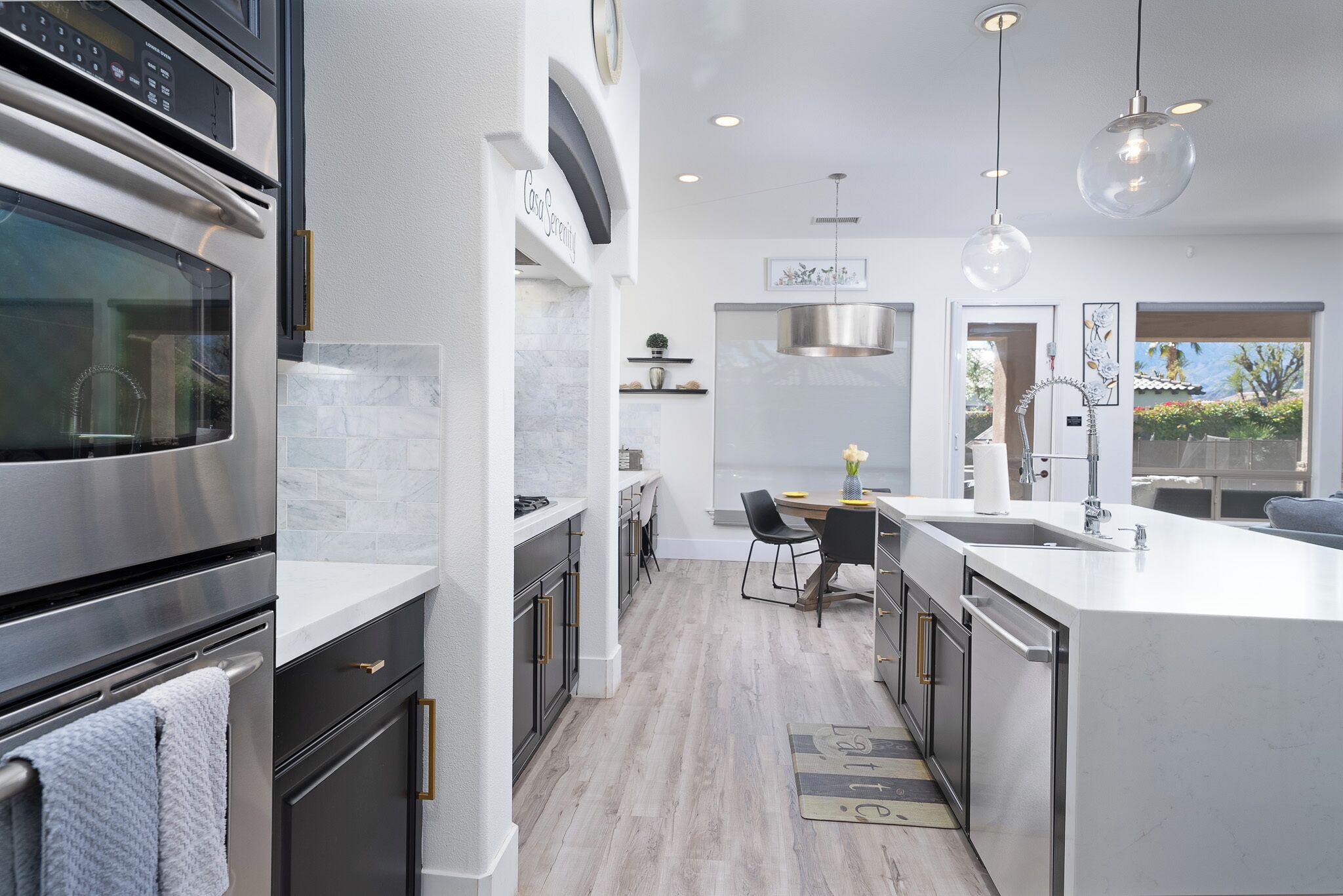 A modern kitchen with a built-in oven, stainless steel appliances, and a central island with a sink.