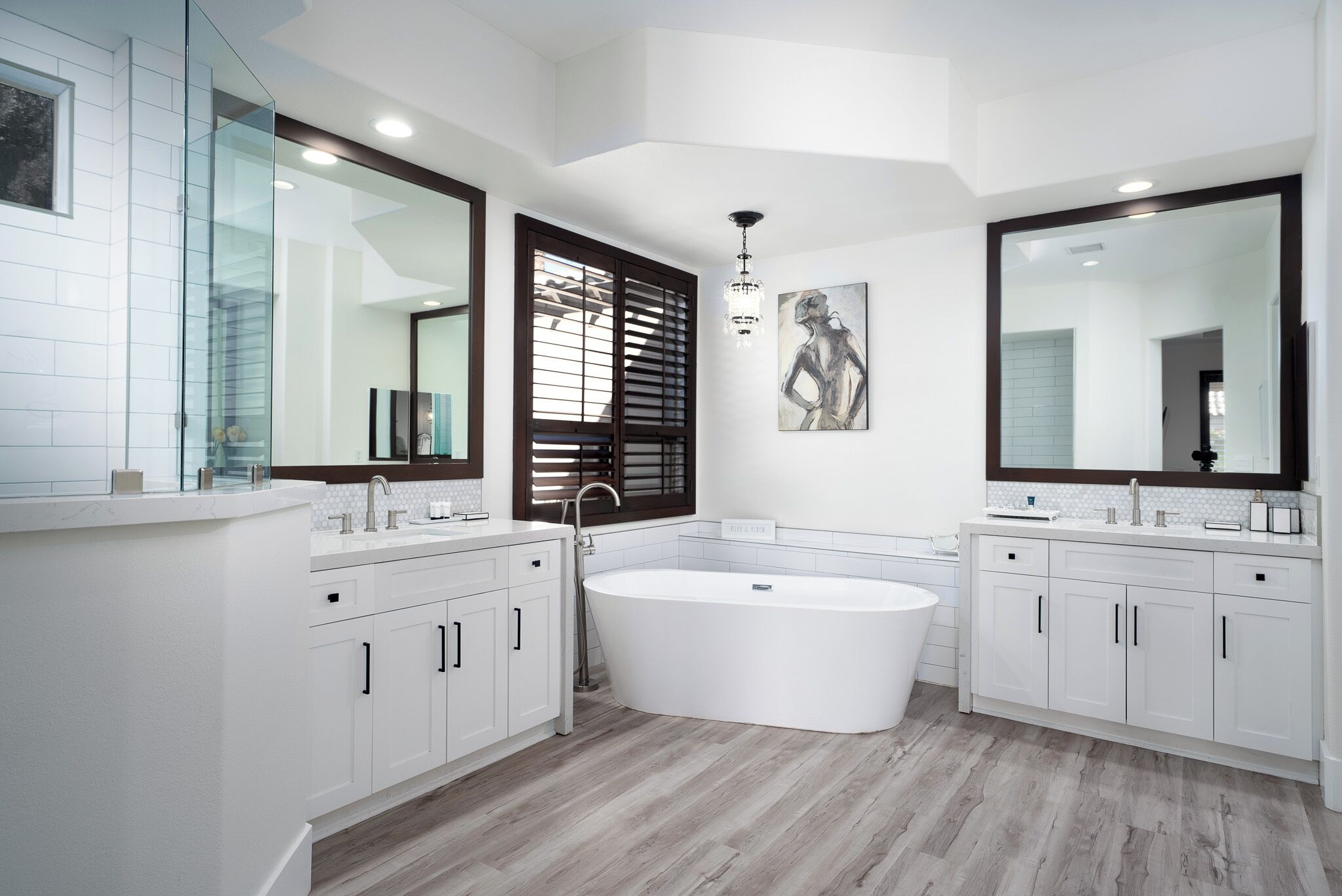 A modern bathroom with a freestanding bathtub, double sinks, and large mirrors.
