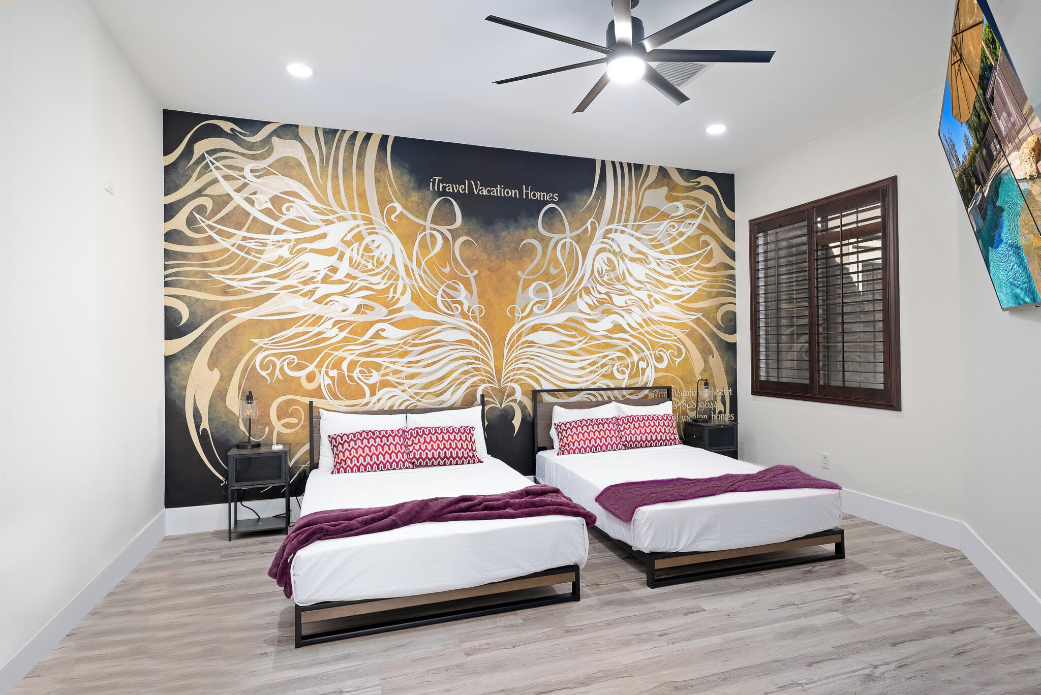 A bedroom with two beds, a ceiling fan, and a wall mural.