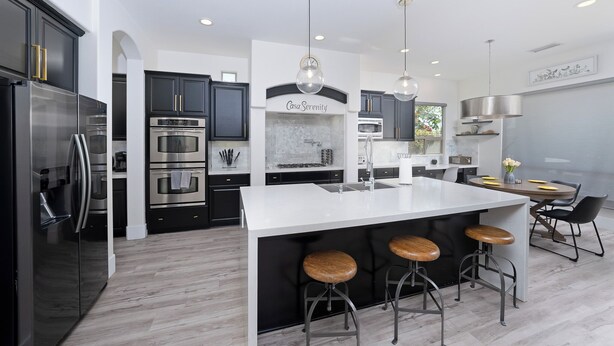 A modern kitchen with a central island, bar stools, stainless steel appliances, and a dining area with a round table and chairs. - Casa Serenity Luxury Living w/ Pool & Jacuzzi (Indio)