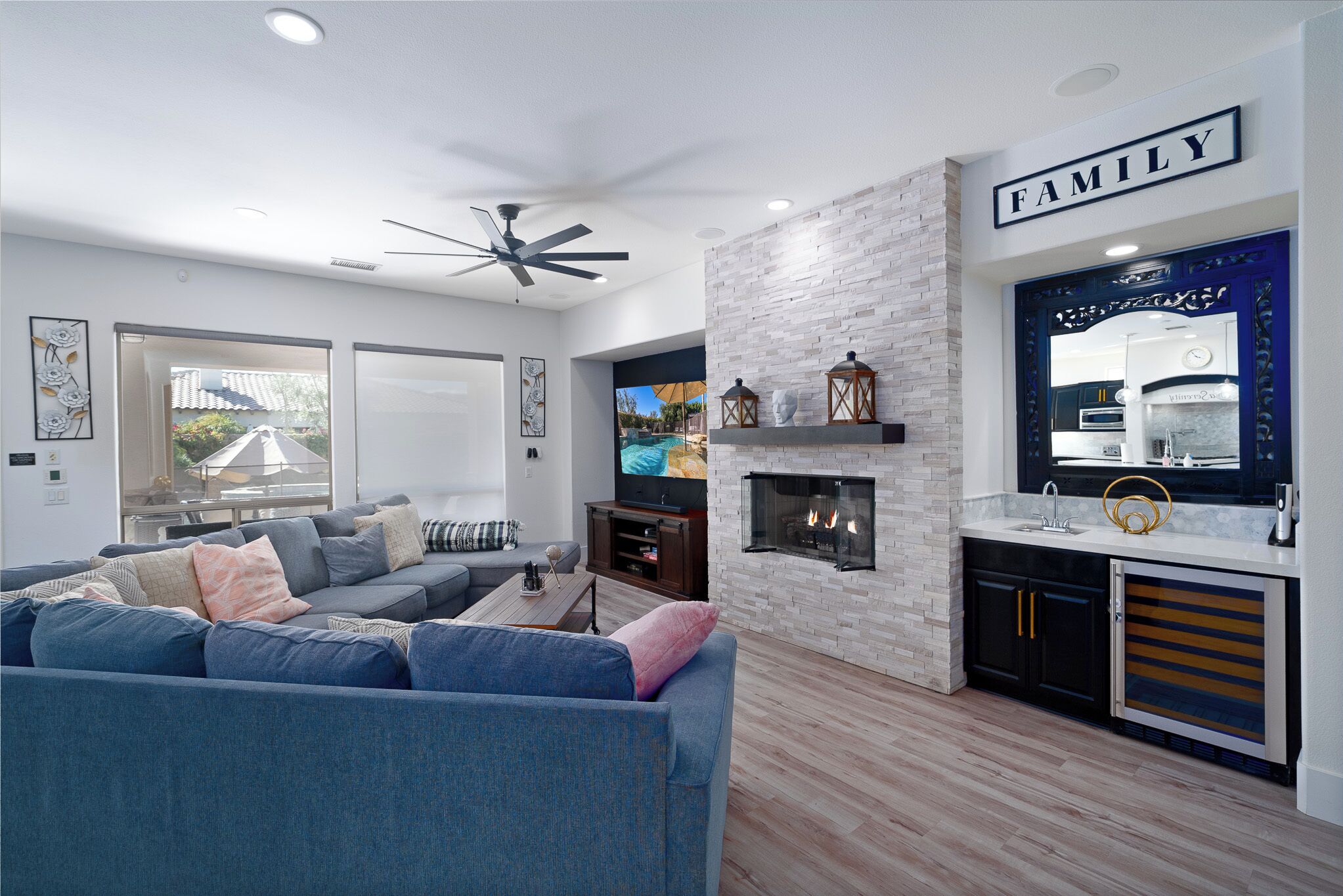 A modern living room with a grey sofa, a fireplace, and a kitchen area with a 'FAMILY' sign.