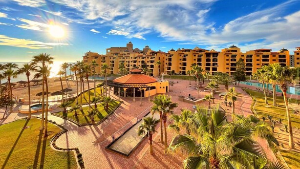 A resort with multiple buildings, a swimming pool, palm trees, and a sunlit courtyard. - Vibe by the Sea of Cortez @Princesa Resort (Puerto Peñasco, Son)