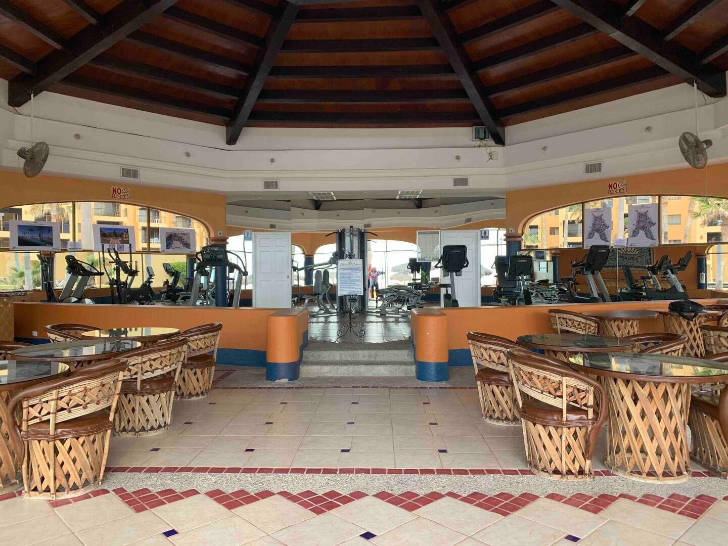 Un gimnasio con equipamiento de ejercicio, muebles de madera y suelo de baldosas.