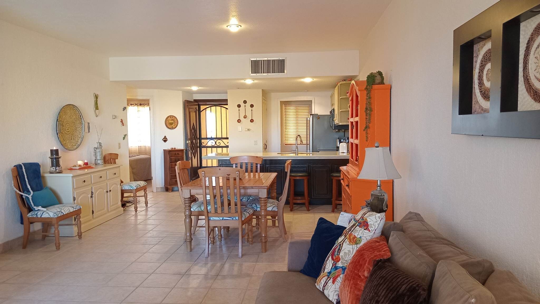 Amplia sala de estar con una mesa de comedor, sillas, un sofá y una cocina al fondo.