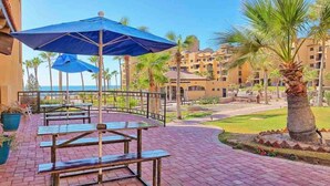 A patio area with outdoor seating, palm trees, and a view of the ocean. - Vibe by the Sea of Cortez @Princesa Resort (Puerto Peñasco, Son)