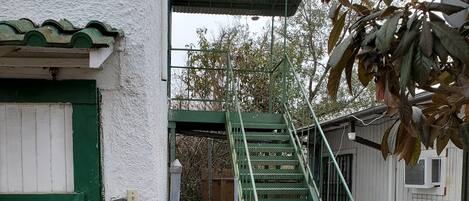 Een trap die leidt naar een gebouw met een groene deur en een witte gevel.