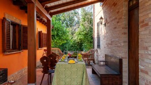 An outdoor dining area with a table set for four, surrounded by wicker chairs, under a wooden pergola. - Lovely home in Morrovalle (Morrovalle)